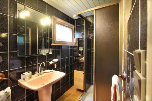 une salle de bain carrelée noire avec un lavabo et une fenêtre dans l'établissement Chalet exposition sud le Nid Douillet, à Gérardmer