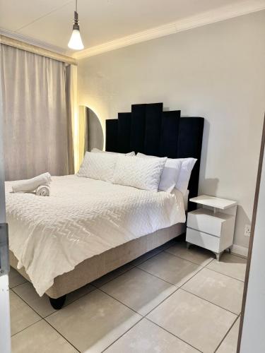 a bedroom with a large bed with a black headboard at The Blyde 104 in Pretoria