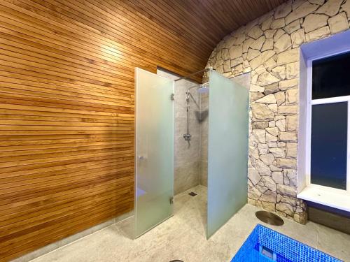 a bathroom with a shower and a stone wall at Casa Cedru in Ialoveni