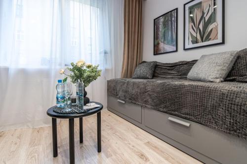a living room with a couch and a table with flowers at Apartly - City Home &B in Szczecin