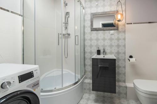 a bathroom with a shower and a washing machine at Apartly - City Home &B in Szczecin