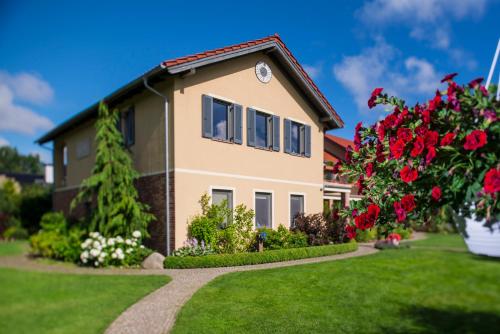 a house with a garden and red roses at Villa Mare Apartamenty in Grzybowo