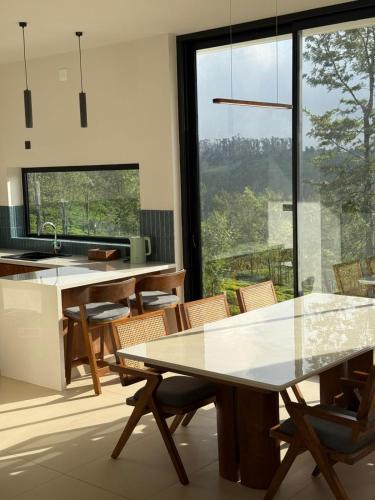 a kitchen with tables and chairs and a large window at Ozone The Misty Villa - Hill View in Coonoor