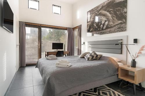 a bedroom with a large bed with a desk and a window at Panorama Beach Villa 4p - Premium Comfort & Uitzicht - Villa 25 in Ouddorp