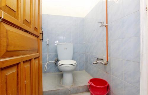 a bathroom with a toilet and a red trash can at OYO 94936 Pondok Purnama in Ciwidey