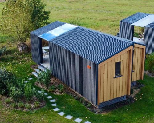 ein kleiner Schuppen mit blauem Dach auf einem Feld in der Unterkunft Tiny House im Grünen 101 - Terrasse, WLAN, Wiesenblick in Barförde