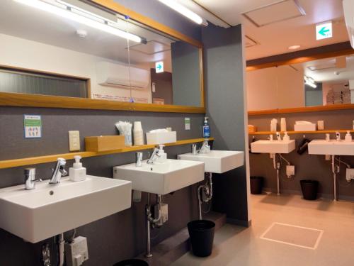 ein öffentliches Badezimmer mit drei Waschbecken und Spiegeln in der Unterkunft ゲストハウス ブランク Guest House BLANC in Hiroshima