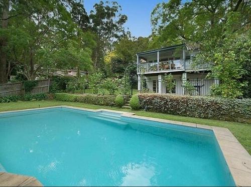 a large blue swimming pool in front of a house at Self-contained unit in Wahroonga in Warrawee