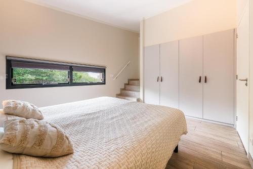 a white bedroom with a bed and a window at Exclusive Duin Villa - 6p - Direct bij Natuur & Strand - Villa 70 in Ouddorp
