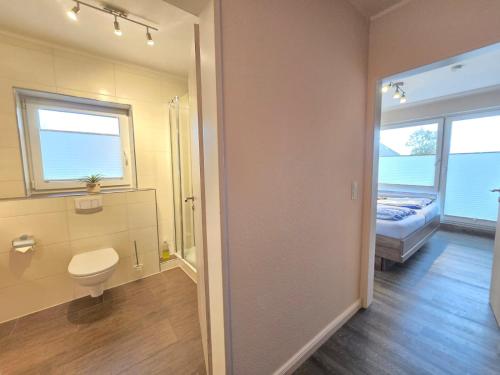 ein Badezimmer mit Toilette, Bett und Fenster in der Unterkunft Ferienwohnung Norddeichurlaub in Norddeich