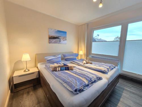 ein großes Bett in einem Zimmer mit zwei Fenstern in der Unterkunft Ferienwohnung Norddeichurlaub in Norddeich