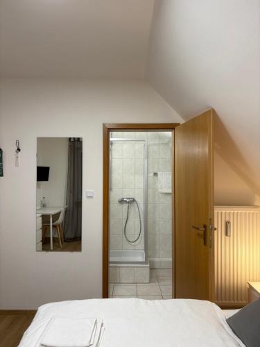 a bathroom with a shower and a bed in a room at Gasthof Wilhelm Tell bei Anna in Zirndorf