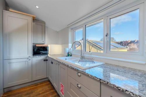 a kitchen with a sink and a large window at Quiet Victorian flat, Gloucester Road, fast wifi in Bristol