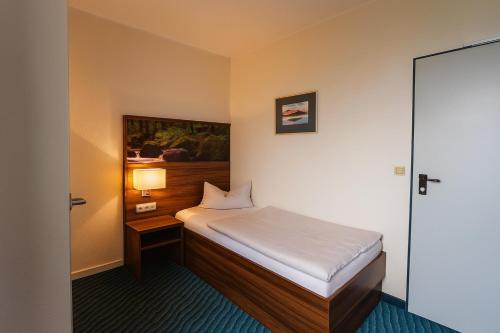 a small bedroom with a bed and a lamp at Bettenburg Hotel Hamburg in Hamburg