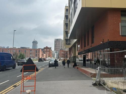 people walking down a city street with a sign on the sidewalk at Joyful Management - Riverview 1 bedroom Apartment 10 min to City Centre in Manchester