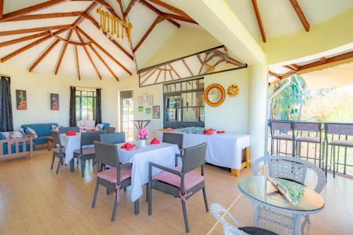 Un comedor con mesas y sillas y ventanas. en Mua Hills Tented Camp, en Katelembu