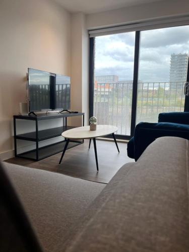 a living room with a tv and a coffee table at Joyful Group - Stylish 2 Bedroom Duplex with Sofa Bed in Salford M5 in Manchester