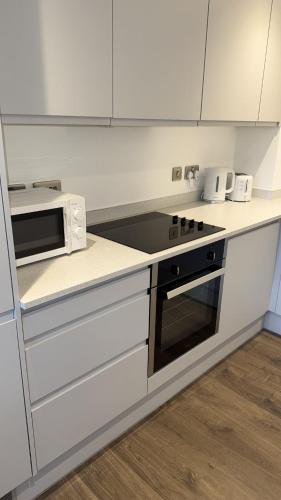 a kitchen with a stove and a microwave at Joyful Group - Stylish 2 Bedroom Duplex with Sofa Bed in Salford M5 in Manchester