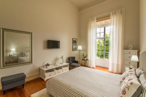 a bedroom with a bed and a mirror and a chair at GuestReady - O Ateneu GuestHouse in Ponta Delgada