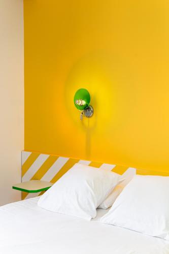 a yellow wall with a bed with a clock on it at OLDEGAR Hôtel in Nantes