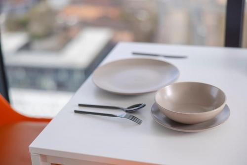 a white table with two plates and a bowl and fork at 2 bed ensuite with fantastic night view and Old Trafford Stadium in Manchester
