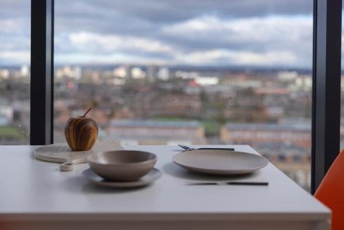 a table with two bowls and an apple on it at 2 bed ensuite with fantastic night view and Old Trafford Stadium in Manchester