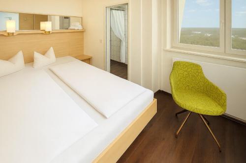 a bedroom with a white bed and a yellow chair at Bettenburg Hotel Hamburg in Hamburg