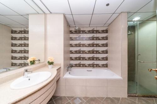 a bathroom with a tub and a sink and a shower at Sunset Beach View Holiday Homes in Ajman 