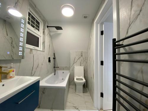 Blindley HeathにあるDippen Hall Signature Apartmentの洗面台、トイレ、浴槽を備えたバスルーム