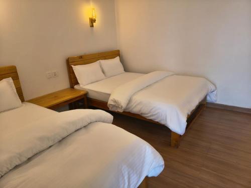 a small room with two beds and a table at RJ Boutique Hotel - Ghandruk in Astam