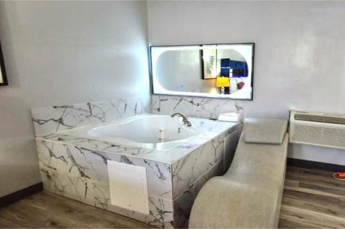 a bathroom with a large tub and a mirror at Capital O Elite Inn & Suites South Holland I 94 in South Holland
