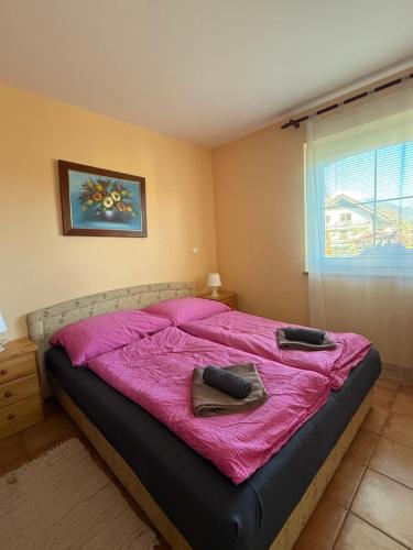 a bedroom with a bed with pink sheets and a window at Apartments and Rooms With View on Bled in Bled