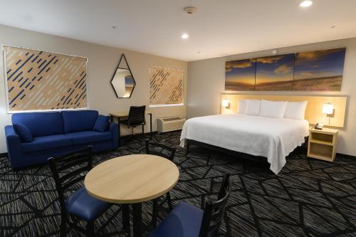 a hotel room with a bed and a blue couch at Days Inn by Wyndham Jackson in Jackson