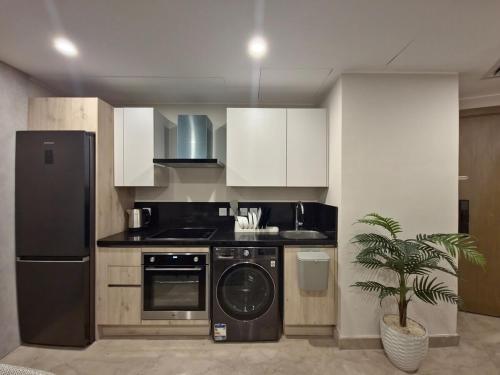 een keuken met een zwarte koelkast en een vaatwasser bij Modern ZED Apartment Near Pyramids, ZED Park, GEM in Sheikh Zayed