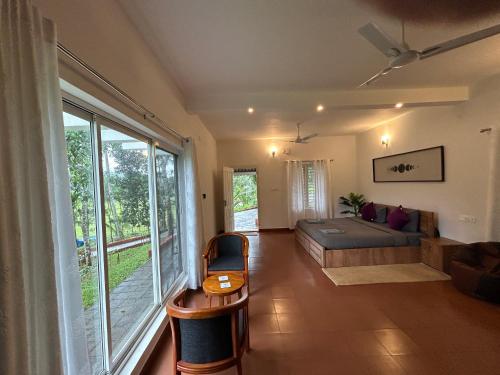 a living room with a bed and a large window at Mahogany by Exuberance Stays in Wayanad