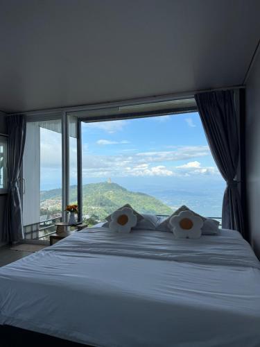 Un dormitorio con una cama con una ventana grande. en วิมานหมอก ภูทับเบิก, en Ban Maeo Thap Boek