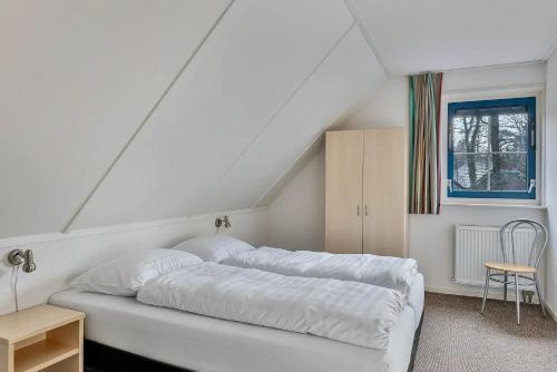 a bedroom with a large white bed in a attic at Zandduin Wellness Villa | 10 personen in Hooghalen