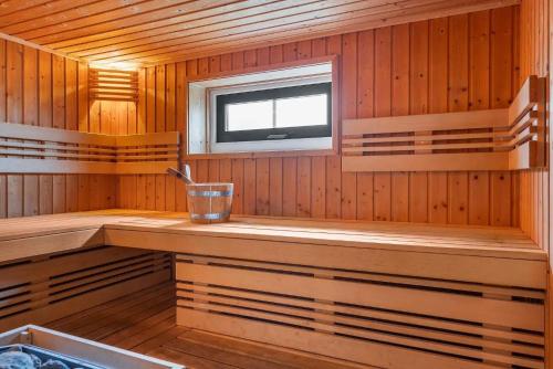 a sauna with a window and a bucket in it at Zandduin Wellness Villa | 10 personen in Hooghalen