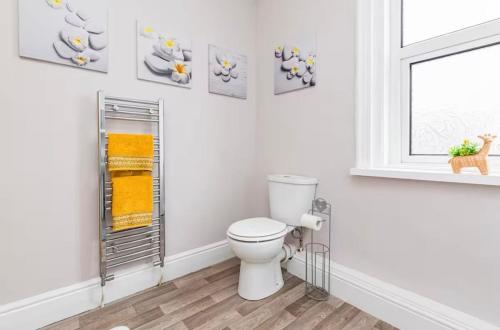 Baño blanco con aseo y cuadros en la pared en Carnarvon Stays - 2 bed home, en Preston