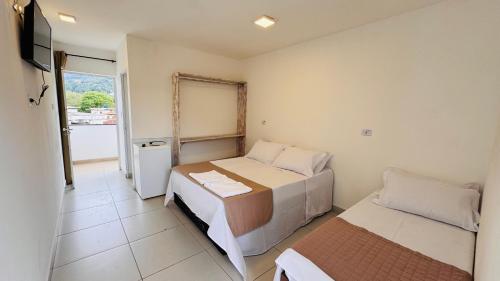 a small room with two beds and a television at Pousada Cahê in Ilhabela