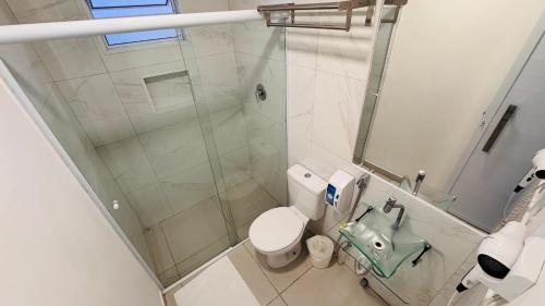 a bathroom with a toilet and a glass shower at Pousada Cahê in Ilhabela