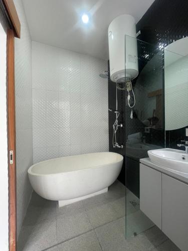 un bagno bianco con vasca e lavandino di Ametys 1 Villa - Cozy 2BR Villa with Private Pool & Prime Seminyak a Seminyak