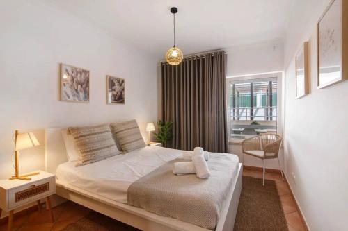 ein Schlafzimmer mit einem Bett und einem Stuhl und einem Fenster in der Unterkunft T2 Santa Luzia F in Santa Luzia