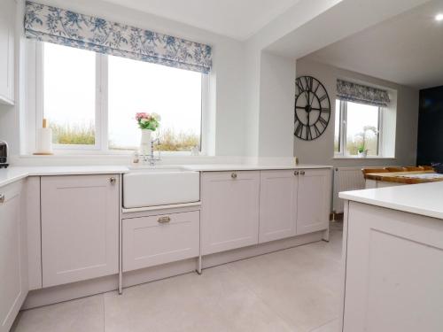 InskipにあるBrook Houseの白いキャビネットと窓のあるキッチン
