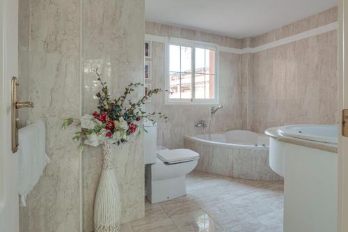 une salle de bains avec des toilettes et une baignoire avec un vase de fleurs dans l'établissement Center beach 2 beds Appartement Elviria, à Marbella