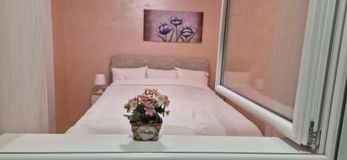 a bedroom with a bed with a vase of flowers at Apartman Blue in Subotica
