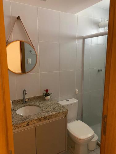 a bathroom with a toilet and a sink and a mirror at Village 2 suítes beira mar Itacimirim in Camaçari