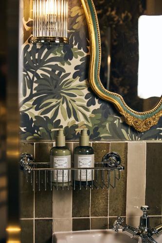 a bathroom with three bottles of soap on a shelf next to a sink at Brownsover Hall Hotel in Rugby