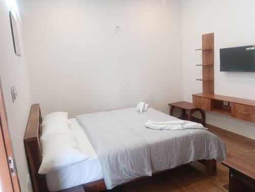 Schlafzimmer mit einem Bett mit weißer Bettwäsche und einem TV in der Unterkunft Le Sasvik in Kodaikanal