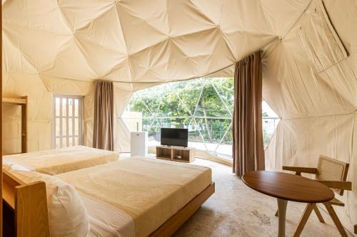 een slaapkamer met 2 bedden en een tafel en een televisie bij Bubble Glamping 2 King beds, we have a 12 units like this in Laguna del Higüero
